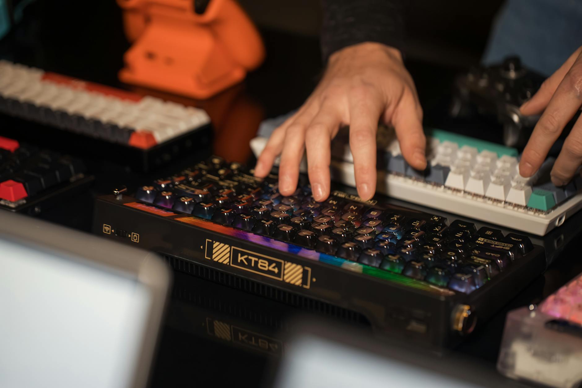 Close-up of hands typing on vibrant custom mechanical keyboards indoors.